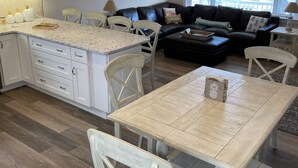 Une cuisine moderne avec des meubles blancs, un plan de travail en granit et des luminaires suspendus.