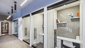 A modern office space with glass partitions, white desks, and a clean, minimalist design.