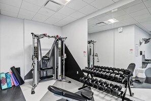 Une salle de sport équipée d’un support à squats, d’un banc et d’haltères.