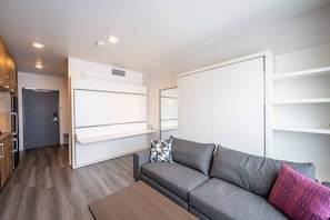 Un salon moderne avec un canapé gris, une table basse en bois et un meuble blanc fixé au mur.