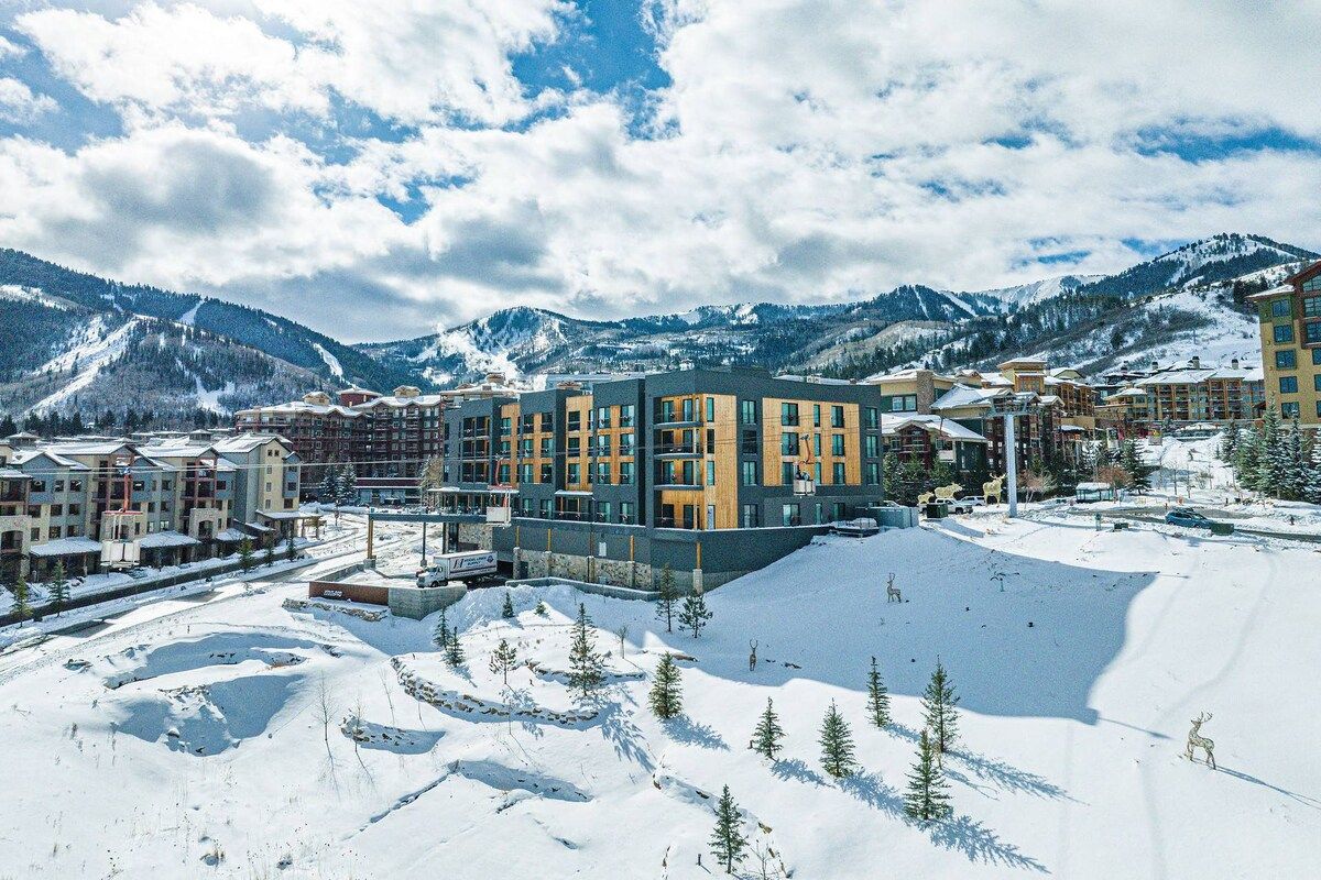 Een winters resort met moderne gebouwen, skipistes en een bergachtige achtergrond.