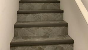 Eine Treppe mit modernem Design, deren Stufen ein geometrisches Muster aufweisen und ein weißes Geländer.