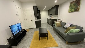Ein modernes Wohnzimmer mit Fernseher, Sofa und Couchtisch.