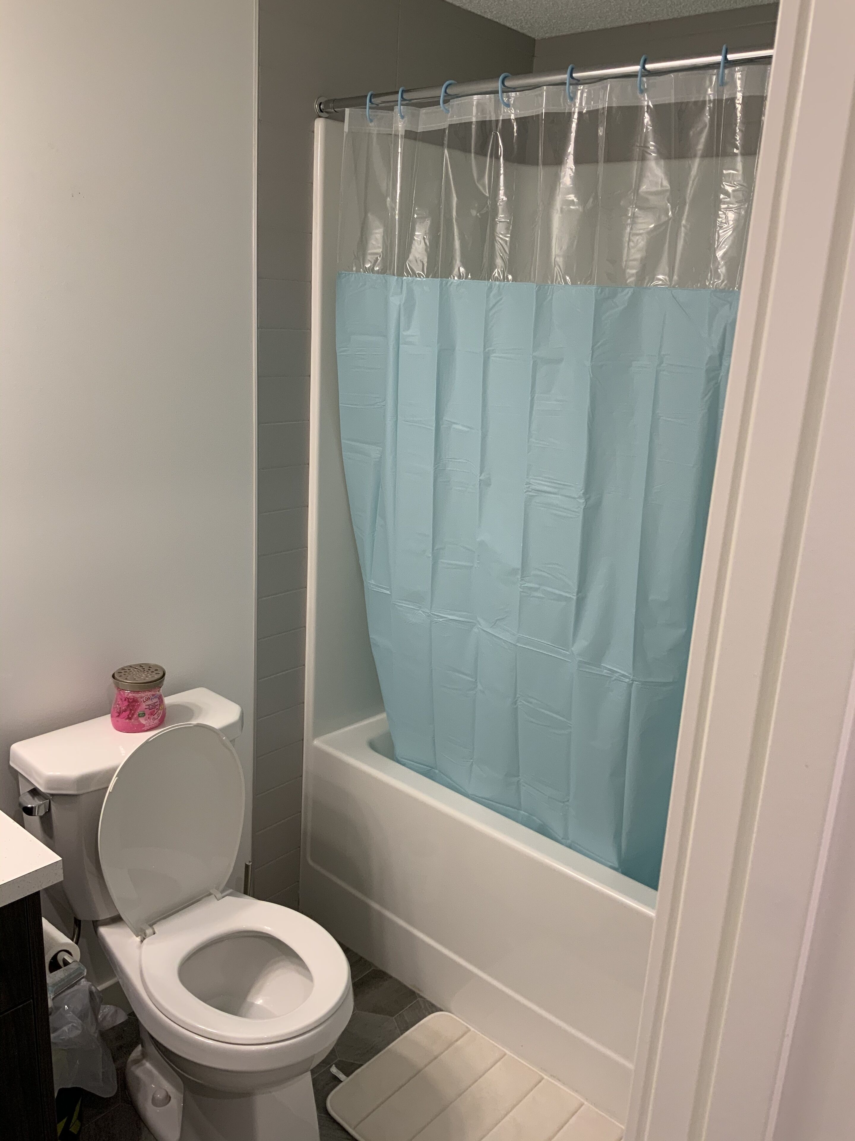 Een badkamer met een wit toilet, een bad en een douchegordijn.