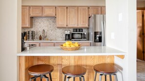 A kitchen with wooden cabinets, a marble countertop, a stainless steel refrigerator, and a bowl of lemons. - Cloud 9 by AvantStay | Located at the Base of Vail Ski Resort w/ Fire Pit + BBQ (Vail)