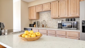 A kitchen with wooden cabinets, a marble countertop, a bowl of lemons, a coffee maker, and a microwave. - Cloud 9 by AvantStay | Located at the Base of Vail Ski Resort w/ Fire Pit + BBQ (Vail)