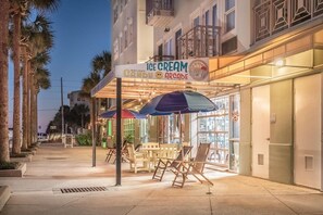 An outdoor seating area with umbrellas and chairs in front of an ice cream arcade.