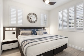 A bedroom with a bed, bedside tables, a mirror, and windows with shutters. - 300 Feet from the Beach, Steps to the Seasonally Heated Pool - Cabana 111 at Gulf Place on 30A (Santa Rosa Beach)