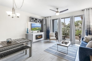 A modern living room with a fireplace, a television, and a dining area. - 300 Feet from the Beach, Steps to the Seasonally Heated Pool - Cabana 111 at Gulf Place on 30A (Santa Rosa Beach)