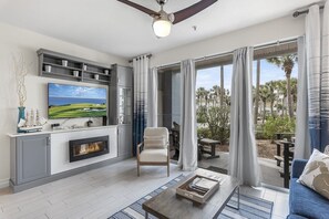 A modern living room with a fireplace, a television, and a view of the outdoors. - 300 Feet from the Beach, Steps to the Seasonally Heated Pool - Cabana 111 at Gulf Place on 30A (Santa Rosa Beach)