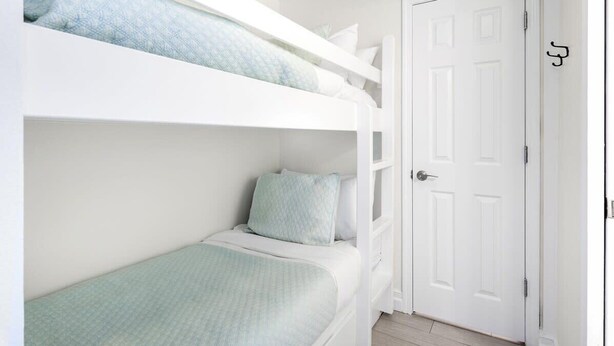 Quarto com beliche, porta branca e janela pequena.