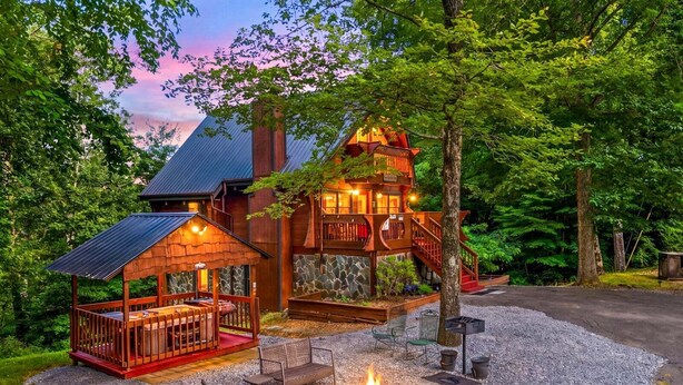 A lodge with a wooden deck, a fire pit, and a stone fireplace.