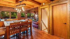 A wooden interior with a dining area, a sofa, and a staircase.