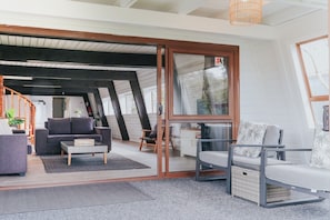 A modern interior with a staircase, a sofa, a coffee table, and a wicker basket. - Lakefront Living at its Best | Private Jetty & Kayaks (Rotorua)