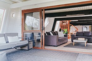 A modern living room with a sliding glass door leading to a staircase. - Lakefront Living at its Best | Private Jetty & Kayaks (Rotorua)