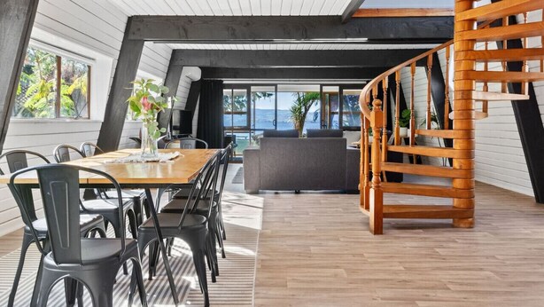 Un espai modern estil loft amb zona de menjador, sofà i escala de fusta.