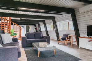 A modern living room with a sofa, coffee table, and a TV on a wooden cabinet. - Lakefront Living at its Best | Private Jetty & Kayaks (Rotorua)