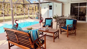 Ein überdachter Außenbereich mit Pool, Holzmöbeln und Blick ins Freie.