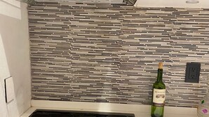 Una cocina con tope de inducción negro, campana de cristal y salpicadero de azulejos.