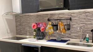 Una cocina moderna con armarios negros, un lavavajillas de acero inoxidable, un microondas y un lavabo con grifo. Hay un florero con flores en la encimera.
