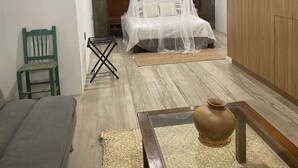Un dormitorio con una cama bajo un dosel, una escalera de madera y una silla verde.