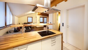 A modern kitchen with a wooden countertop, stainless steel range hood, and a built-in stove. - Apartment "Huck" with Mountain View, Balcony & Wi-Fi (Karneid)