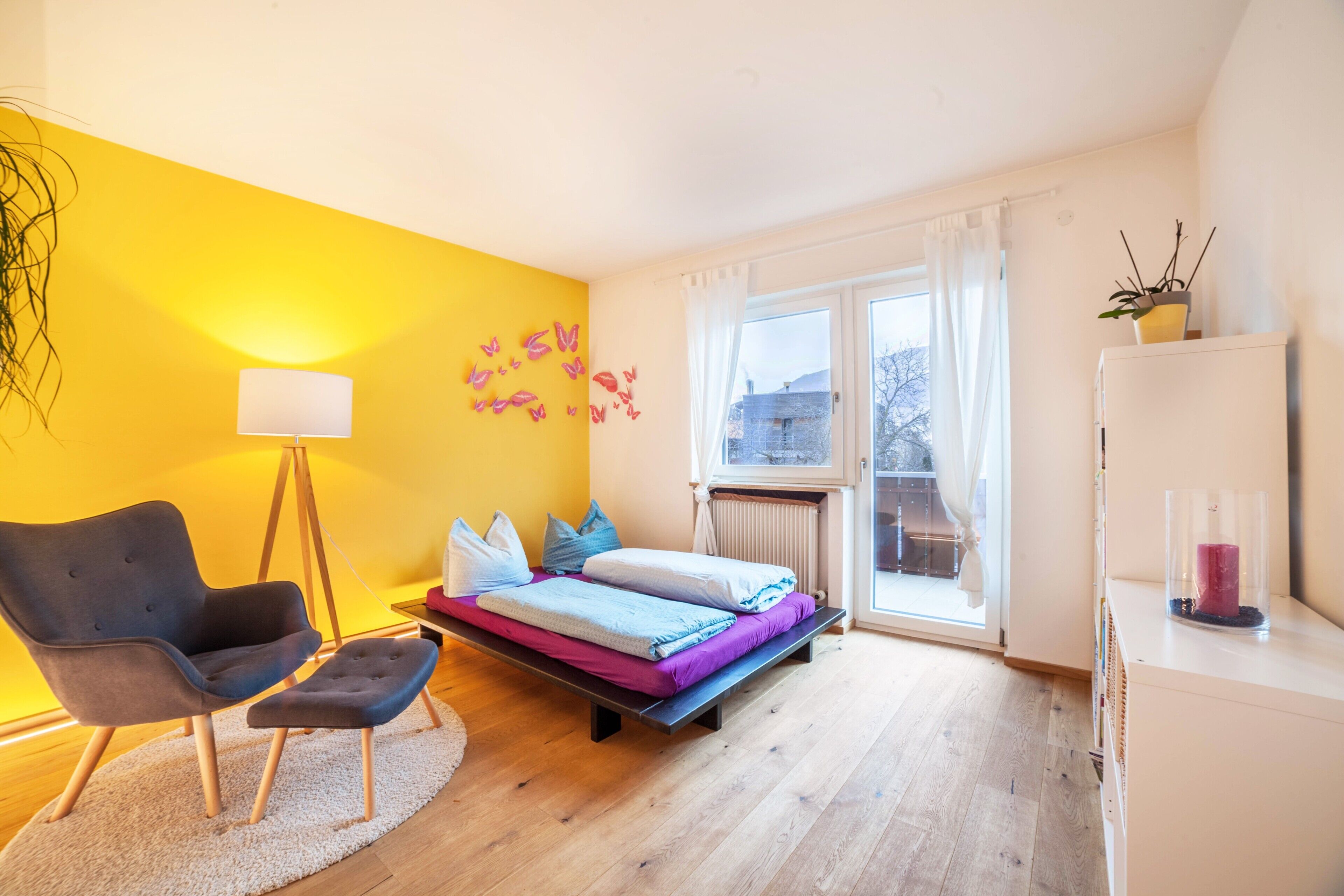 Ein Schlafzimmer mit Bett, Stuhl, Lampe und Fenster.