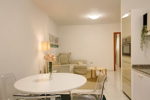 A modern kitchen with white cabinets, a built-in oven, and a small dining area with a round table and chairs. - Apartment 'Little Gem' in a Central Location with Wi-Fi (Cruce de Arinaga)