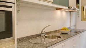 Eine Küche mit einem Edelstahlspülbecken, einer Arbeitsplatte aus Granit und einer Schüssel mit Obst.