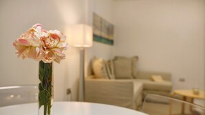 Ein Zimmer mit einem runden Tisch, einer Blumenvase, einer Lampe und einem Sofa.