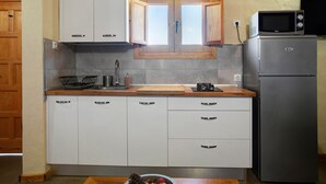A compact kitchen with white cabinets, a built-in microwave, and a stainless steel refrigerator. - Country House 'Casa Rural Los Colorados' with Mountain Views and Pool (Vega de San Mateo)