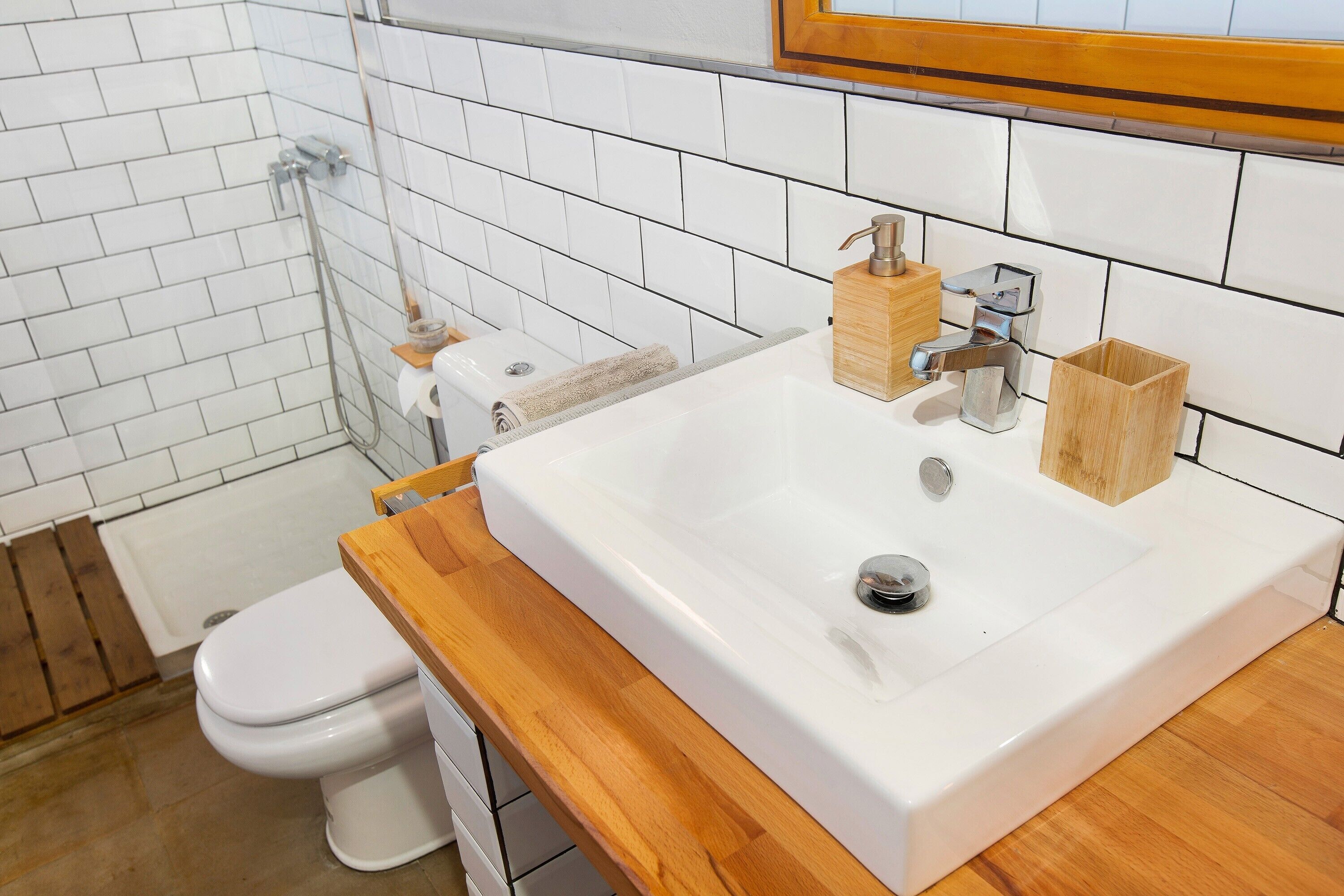 A bathroom with a white sink, wooden countertop, and a toilet.