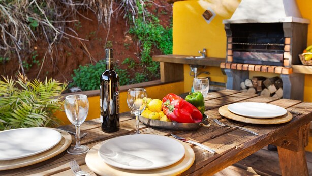 A wooden table set for a meal with plates, cutlery, a bottle, and a bowl of fruit. - Country House 'Casa Rural Los Colorados' with Mountain Views and Pool (Vega de San Mateo)
