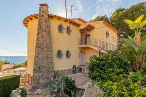 A Mediterranean-style building with a stone column, a balcony, and a view of the sea.