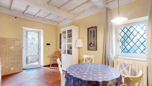 A dining area with a round table, chairs, a cabinet, and a window with a lattice design. - ‘Casa Conte Picedi Appartamento Luna’ Apartment with Sea View (Lerici)