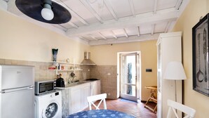 A compact kitchen with a washing machine, a built-in oven, and a dining area with a table and chairs. - ‘Casa Conte Picedi Appartamento Luna’ Apartment with Sea View (Lerici)