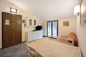 A small, well-lit room with a wooden door, a white cabinet, a television, a table, and a chair. - Pet Friendly Apartment 'Messalina Agriturismo La Scuderia' with Wi-Fi (Andora)