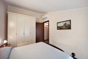 A bedroom with a bed, a wardrobe, an air conditioner, a bedside lamp, and a framed picture on the wall. - Pet Friendly Apartment 'Messalina Agriturismo La Scuderia' with Wi-Fi (Andora)