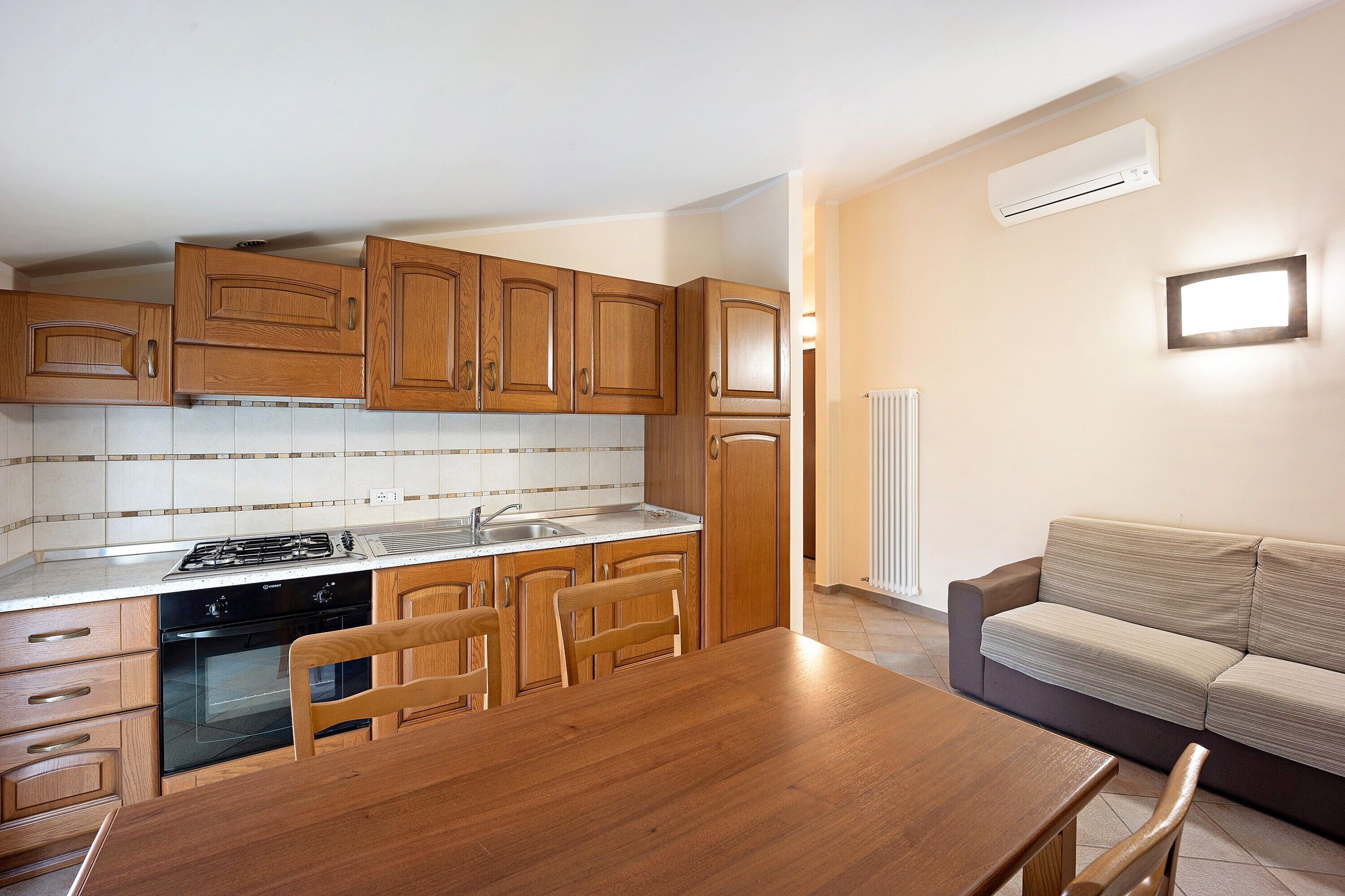 Una cucina con mobili in legno, un fornello e un tavolo da pranzo con sedie.