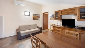 Eine moderne Küche mit Holzschränken, einem Esstisch und einer Couch.