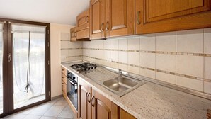 Eine Küche mit Holzausstattung, einem Edelstahlspülbecken und einem Gasherd.