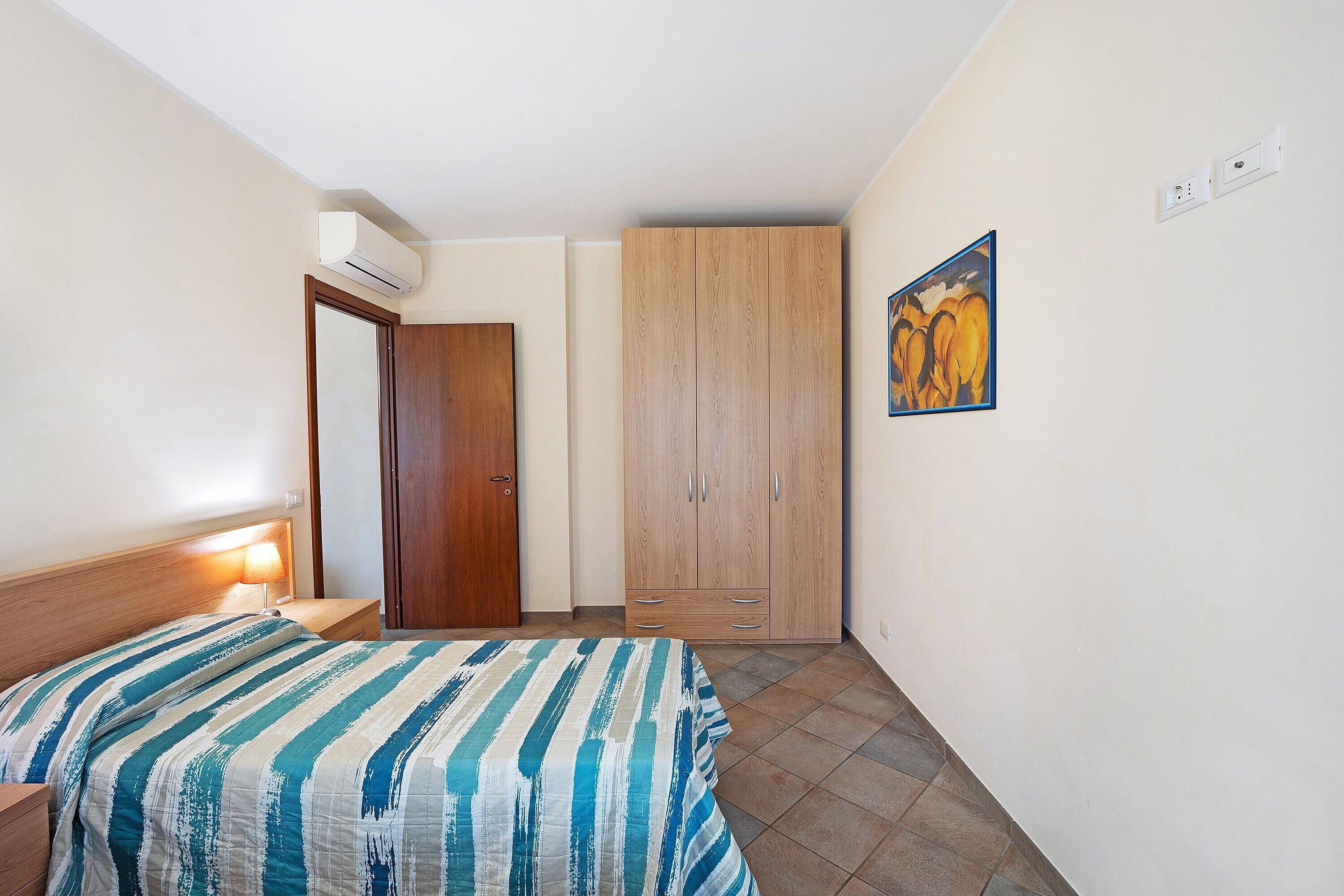 Ein Schlafzimmer mit Bett, Nachttisch, Kleiderschrank und einem Bild an der Wand.