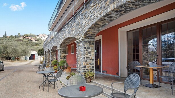 A stone building with outdoor seating and a view of the hillside.
