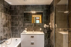 Casa de banho moderna com um espelho grande, uma banheira, toucador com lavatório e zona de duche.