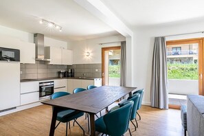 Una cocina moderna con armarios blancos, una mesa de comedor de madera y sillas azules.