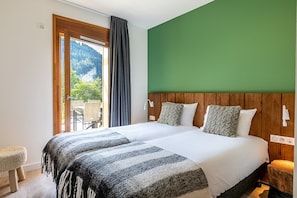 Une chambre avec un grand lit, une tĂȘte de lit en bois, une vue sur la verdure et une fenĂȘtre avec des rideaux.