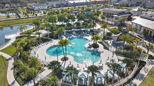 Piscina de un resort con palmeras, sillas de descanso y un pequeño pabellón.