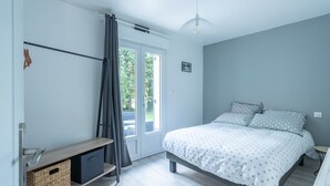 A bedroom with a bed, a wardrobe, a small table, and a door leading to an outdoor area. - Fully self-contained cottage (Inxent)