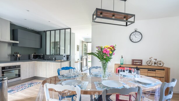 A modern kitchen with built-in appliances, a dining area with a round table and chairs, and a clock on the wall. - Fully self-contained cottage (Inxent)