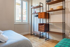 A bedroom with a bed, a wardrobe with shelves, and a window.